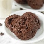 A close up shot of three double chocolate cookies on a small white plate.