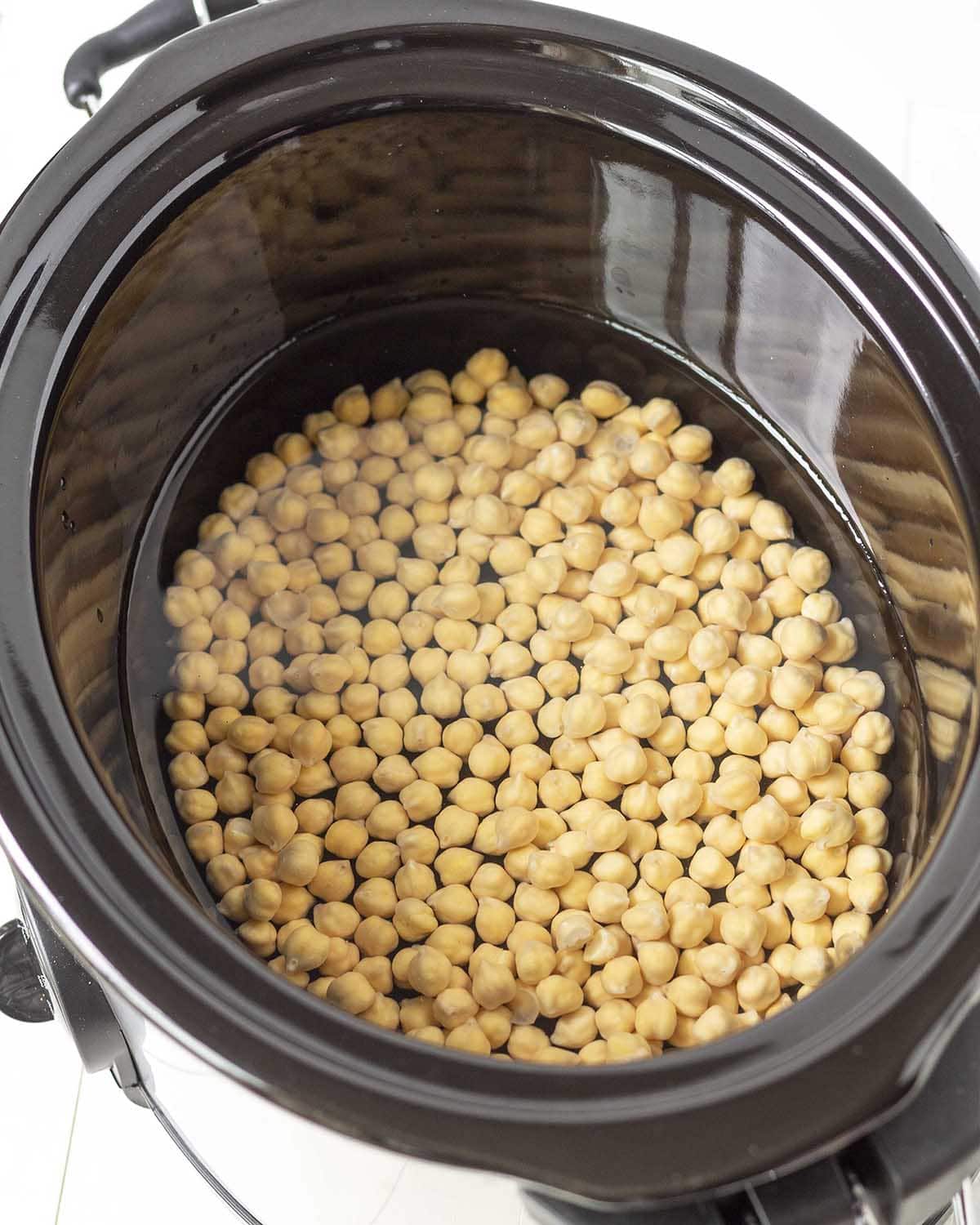 Overhead shot of chickpeas and water in a slow cooker.