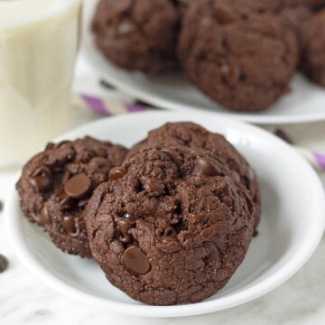 A close up shot of three double chocolate cookies sitting on a small white plate.