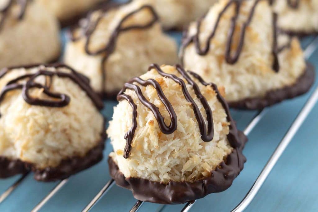 A close up shot of chocolate dipped coconut macaroons on baking rack.