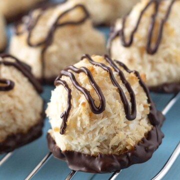 A close up shot of chocolate dipped coconut macaroons on baking rack.