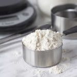 A close up shot of a a measuring cup filled with flour.