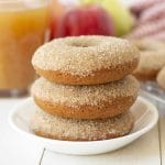 Picture of three vegan gluten-free apple cider donuts stacked on a small white plate.