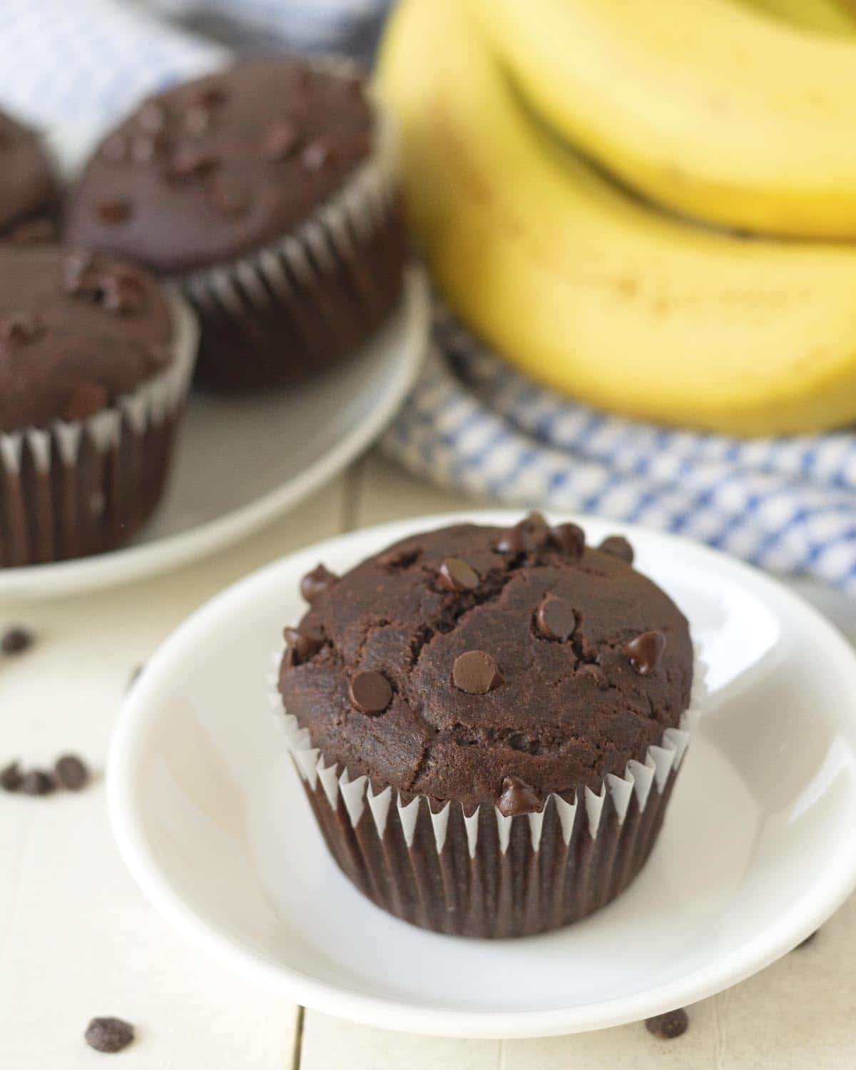 A gluten-free double chocolate banana muffin on a small white plate.