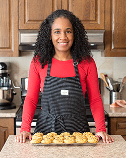 A person standing in front of a tray of cookies.