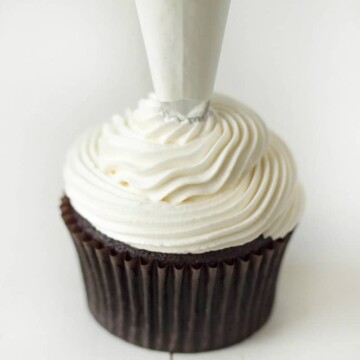 Image shows peppermint buttercream being piped onto a chocolate mint cupcake.