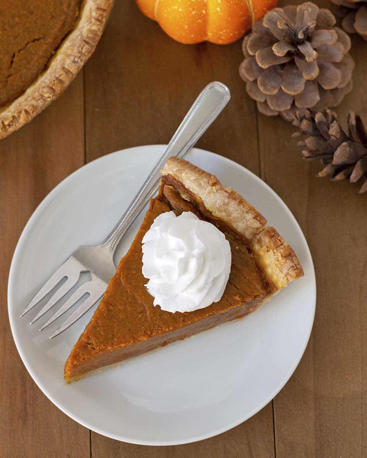 Overhead shot of a slice of vegan pumpkin pie, pie is on a white plate.