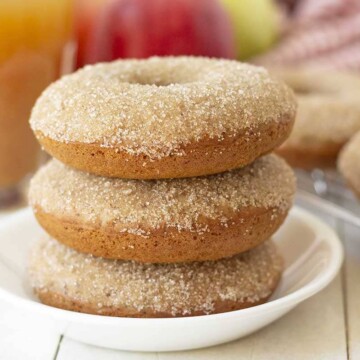 Picture of three vegan apple cider donuts stacked on a white plate.