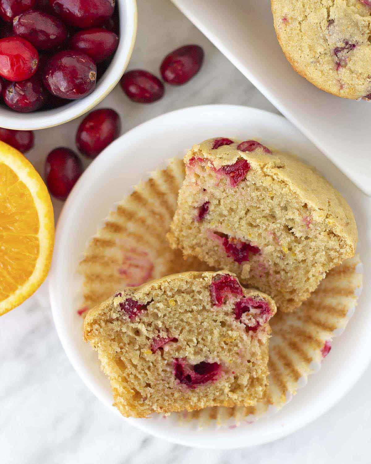 An overhead shot of a cranberry orange muffin split in half to show the fluffy inner texture.