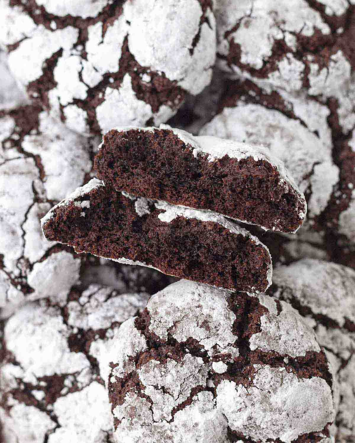 A vegan chocolate crinkle cookie split in two to show the fudgy center.