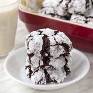 A stack of chocolate crinkle cookies on a small white plate.