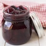 A small glass mason jar filled with cherry sauce dessert topping.