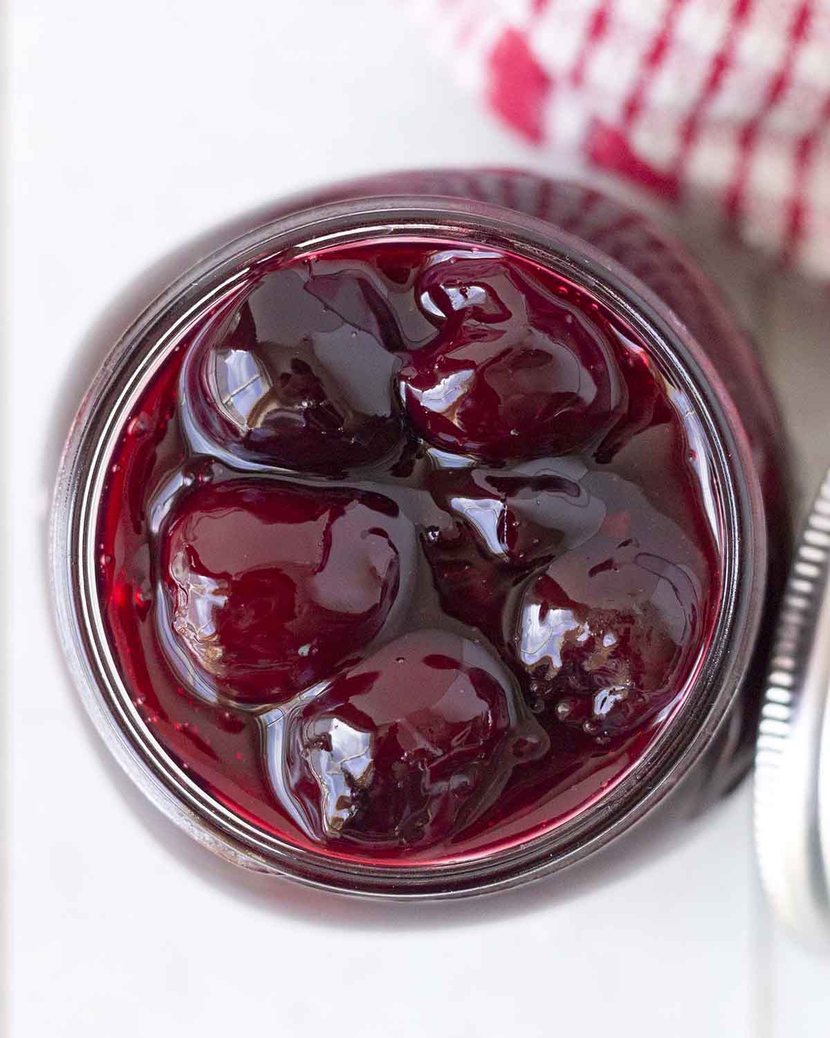 An overhead shot of a mason jar filled with homemade cherry dessert sauce.