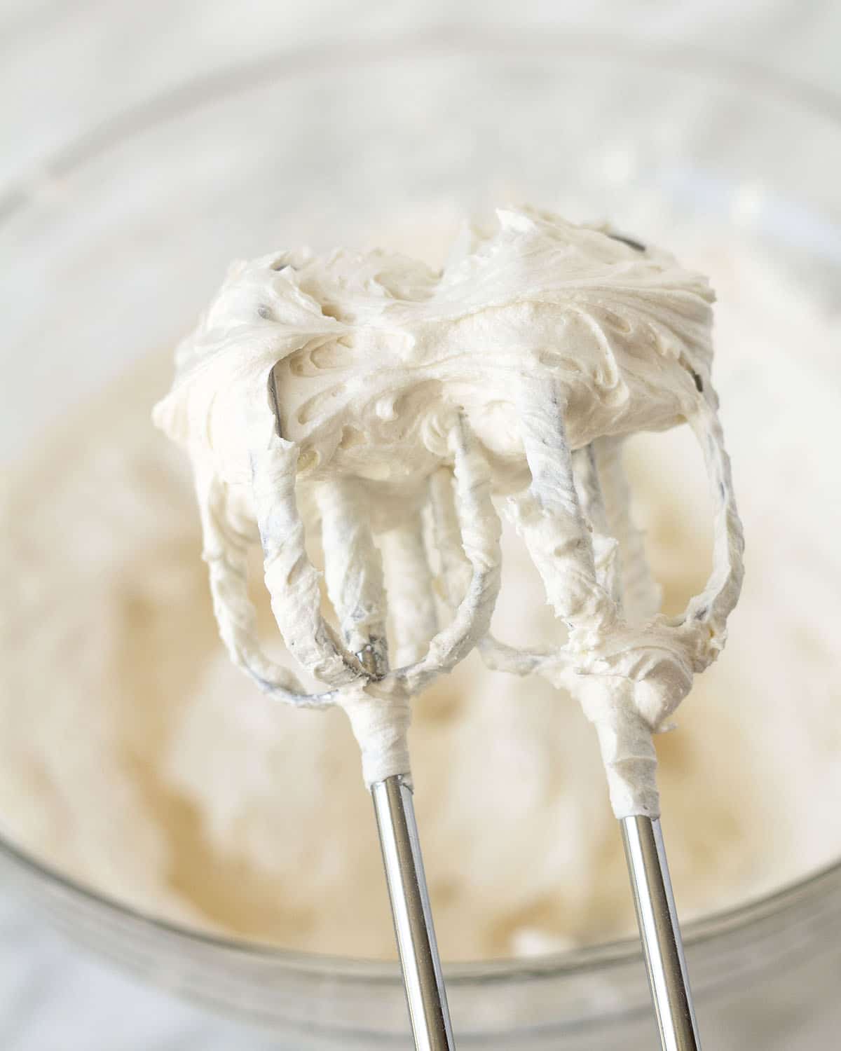 Image shows vanilla frosting on the beaters of an electric mixer.