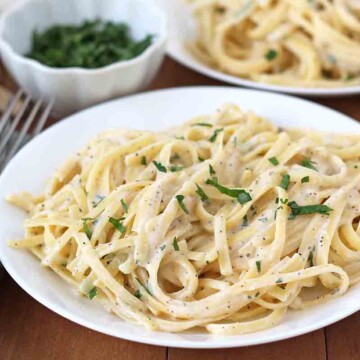 Vegan Garlic Pasta on a white plate, pasta is garnished with fresh parsley.