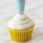 Vegan lemon buttercream frosting being piped onto a lemon cupcake.