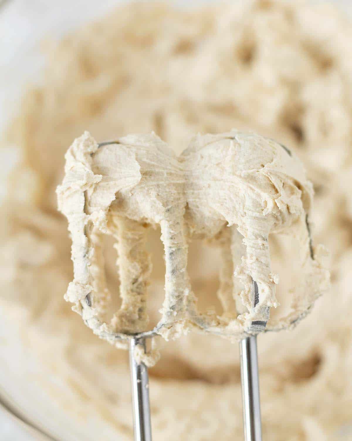 Image shows dairy-free peanut butter buttercream on the beaters of an electric mixer.