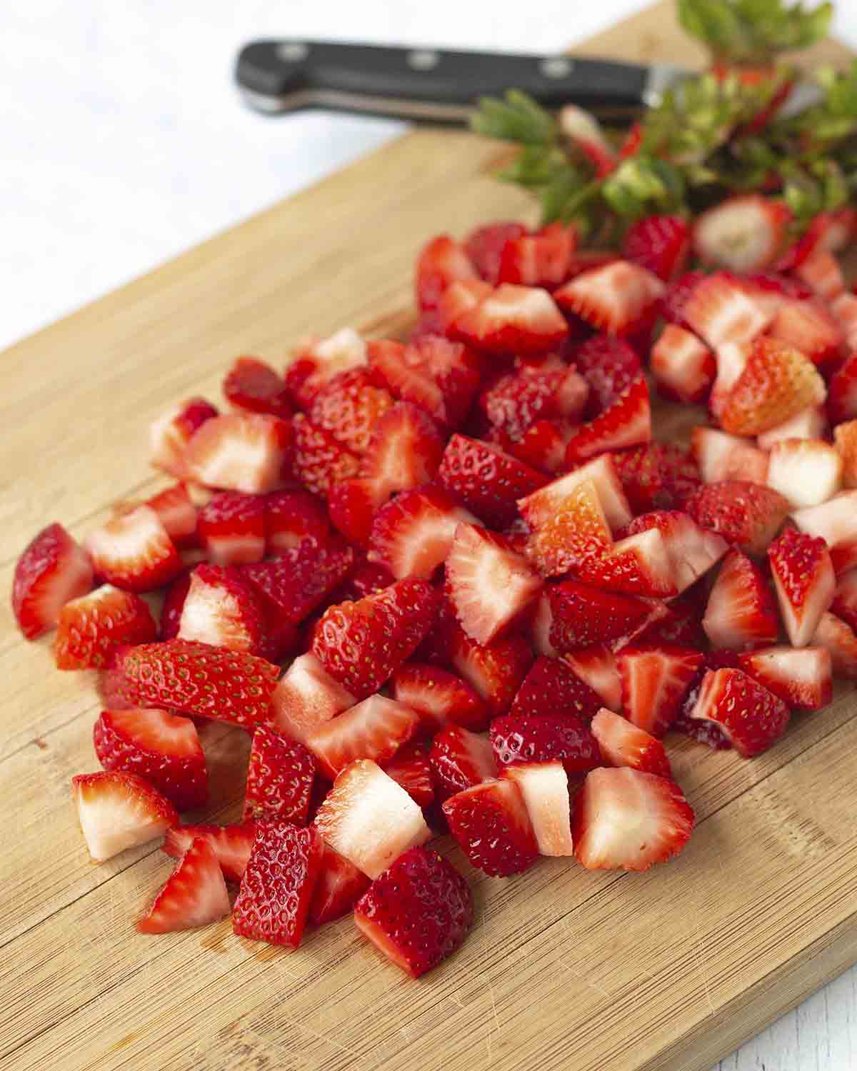 Freshly chopped strawberries on a cutting board.