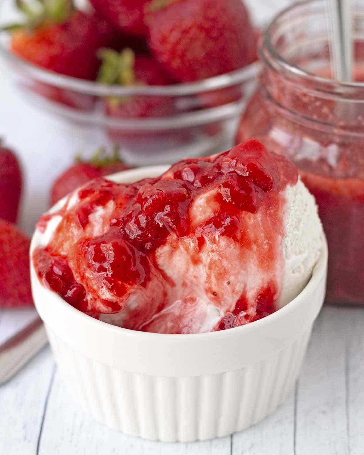A bowl of coconut ice cream topped with strawberry sauce.