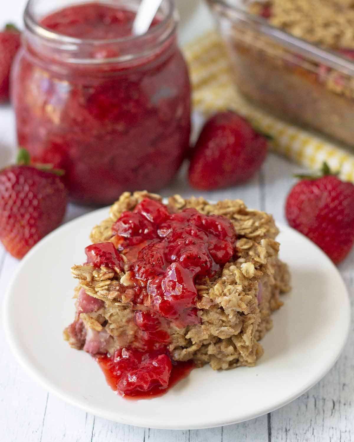 A close up shot showing a slice of egg free baked oatmeal topped with strawberry sauce.