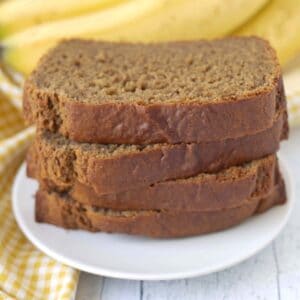 A close up shot showing four slices of egg-free gluten-free banana bread on a white plate.