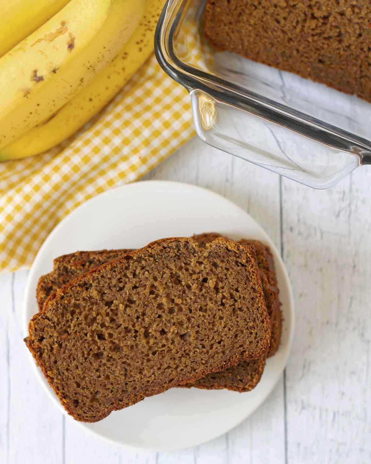 An overhead shot showing three slices of vegan banana bread on a white plate.
