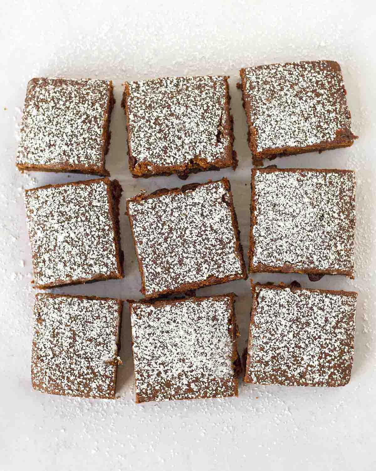 An overhead shot showing vegan applesauce cake sliced into squares with powdered sugar dusted on top.