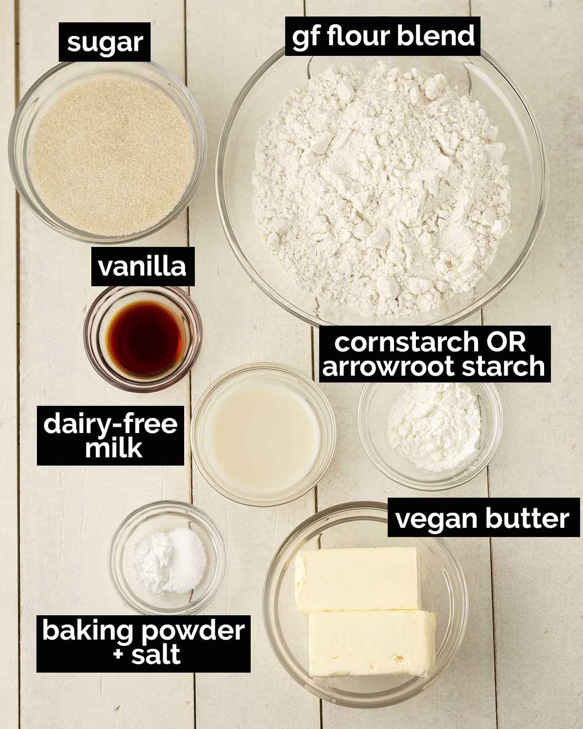 An overhead shot of the ingredients needed to make eggless sugar cookies from scratch, ingredients are in separate bowls.