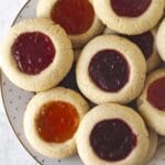 Vegan gluten-free thumbprint cookies stacked on a white plate.