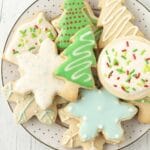 A plate of sugar cookies that have been decorated with eggless royal icing on a festive plate.