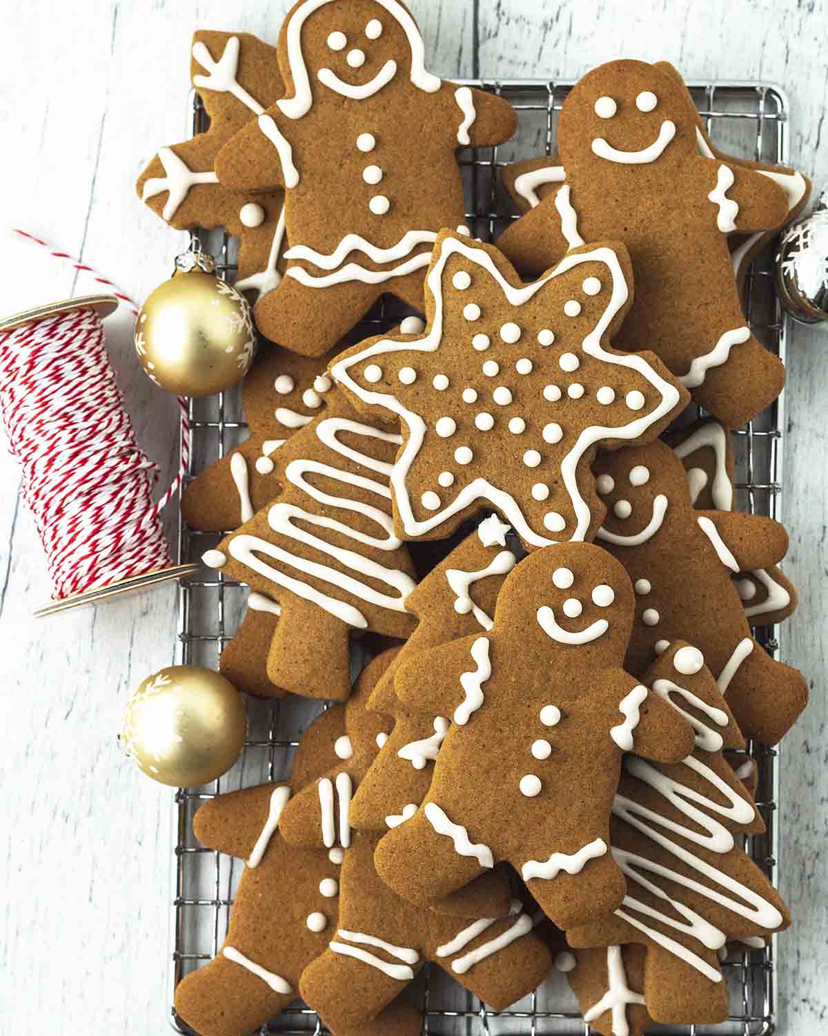 Image shows decorated holiday gingerbread cookies stacked on top of each other on a cooling rack.