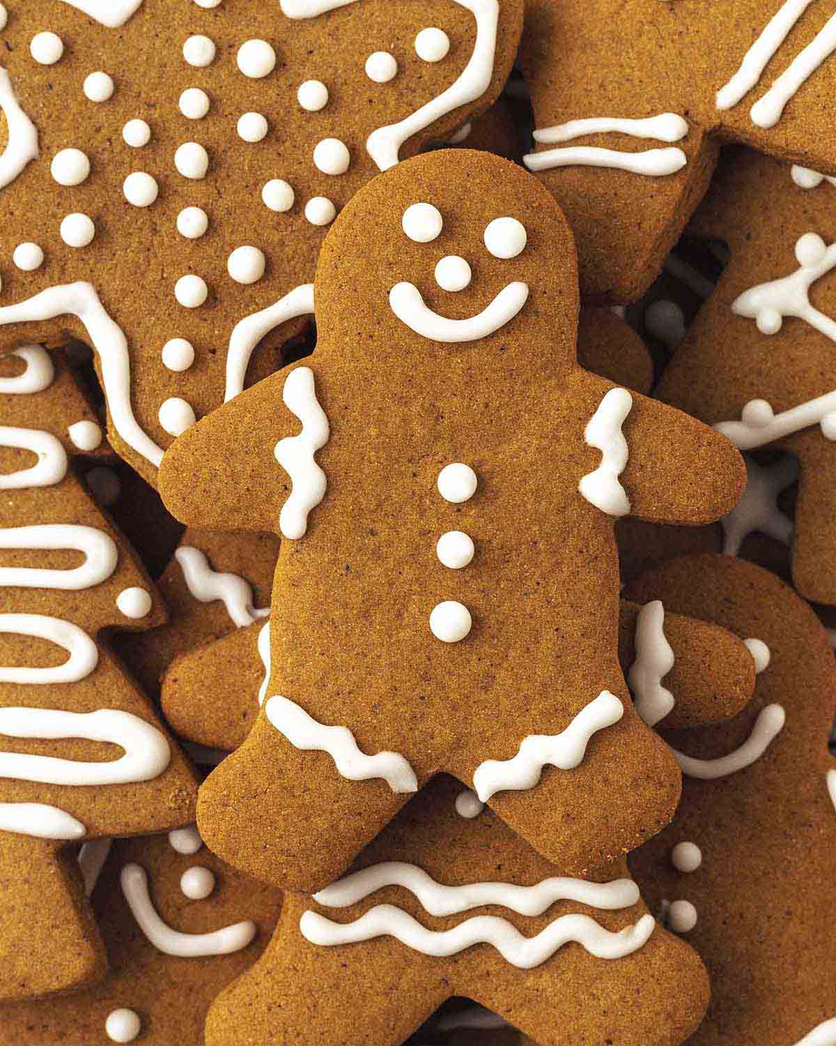 A pile of decorated vegan gingerbread cookies stacked on top of each other with a gingerbread man on top.