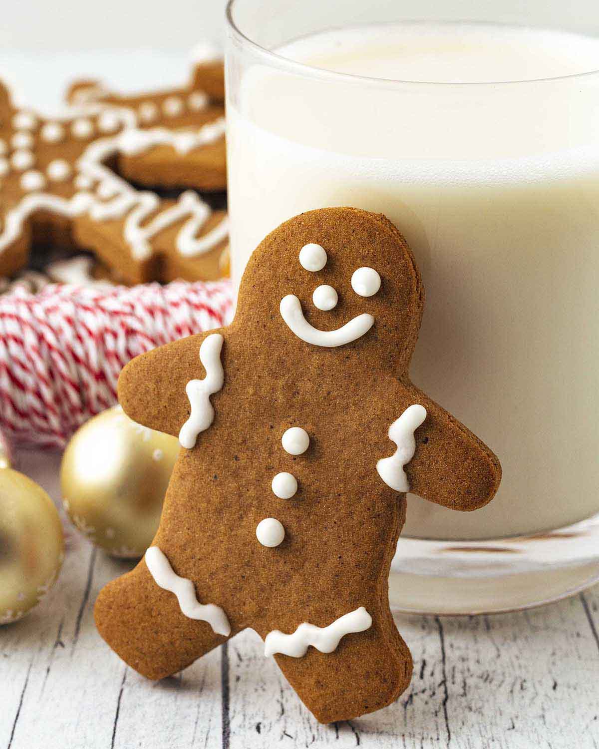A gluten-free gingerbread man cookie leaning on a glass of dairy-free milk.