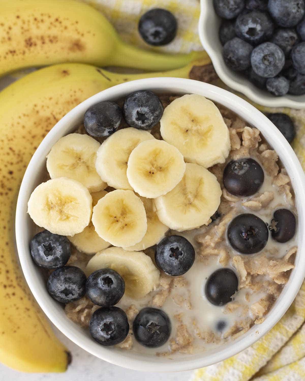 An overhead shot showing a bowl of blueberry banana oatmeal, fresh blueberries and sliced bananas garnish the oatmeal.