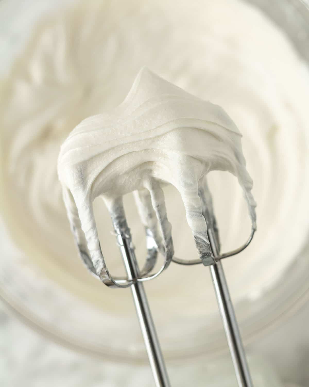 Image shows easy vegan cream cheese frosting on the beaters of an electric mixer.