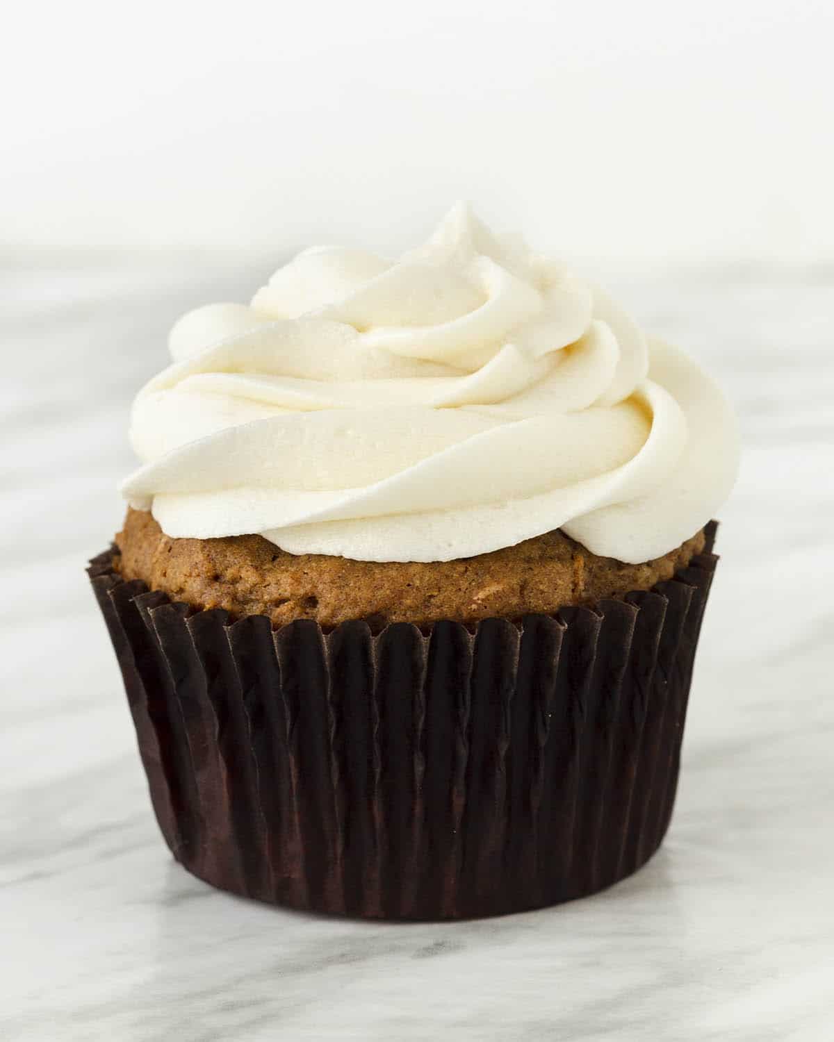 Image shows a carrot cupcake topped with non-dairy cream cheese icing.