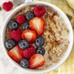 A close up shot showing a bowl of breakfast oatmeal topped with fresh berries.