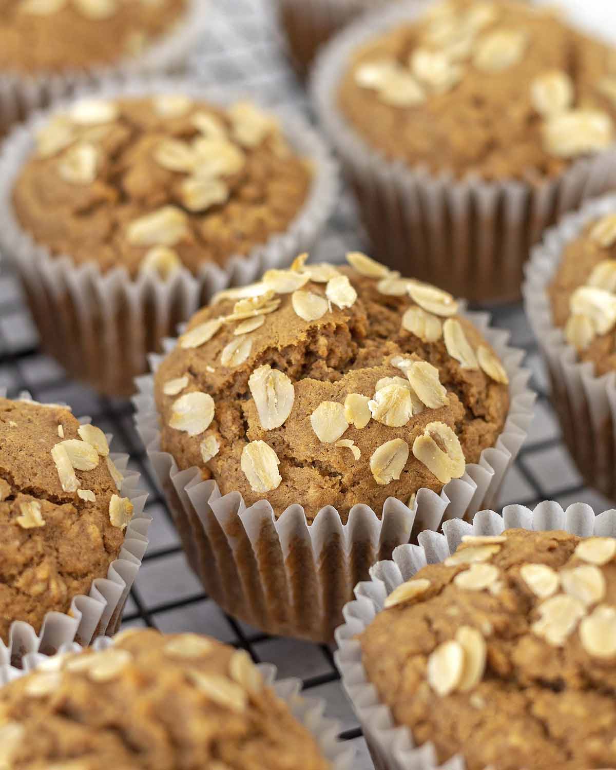Image shows freshly baked oatmeal muffins on a cooling rack.