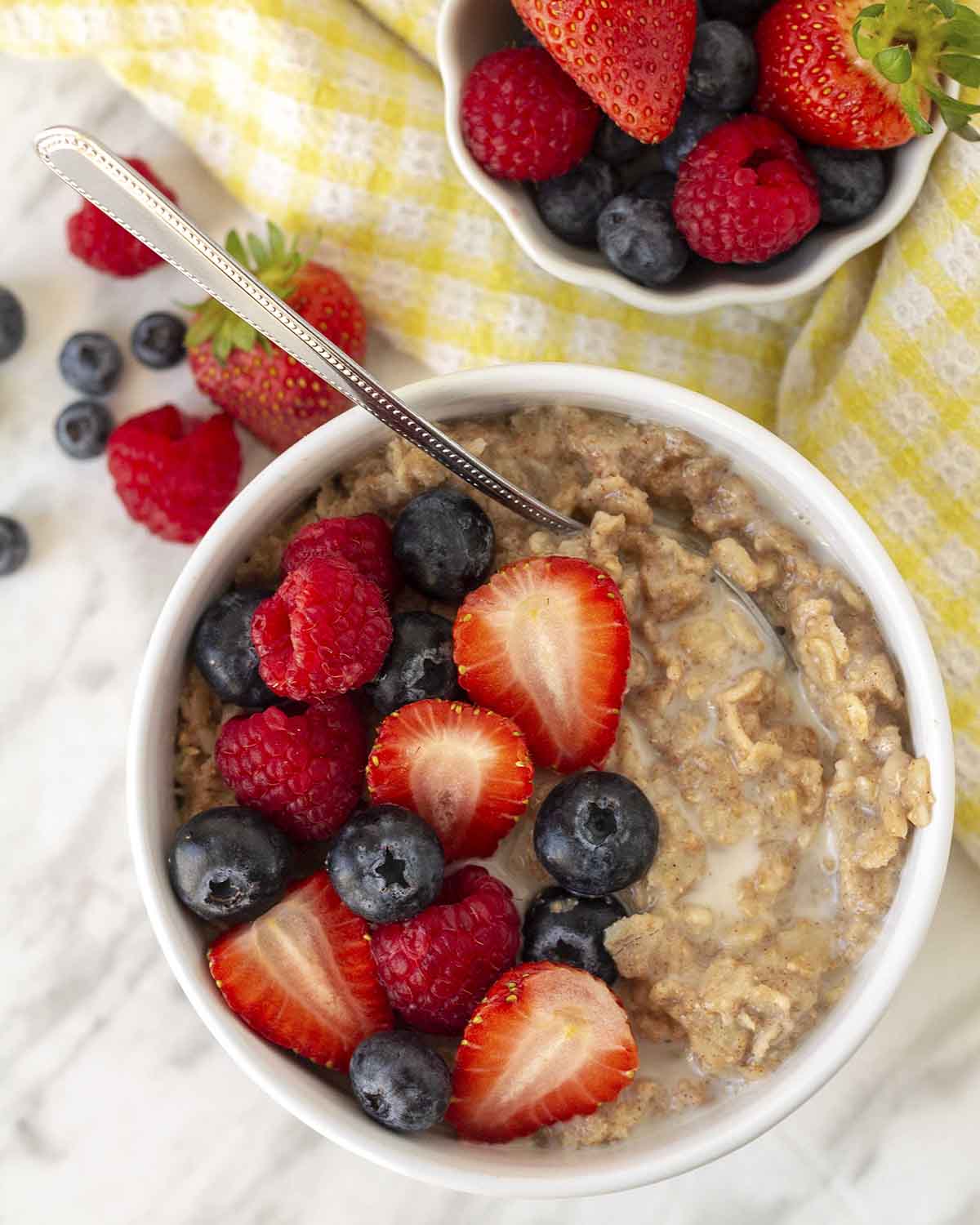 An overhead shot showing a bowl of flaxseed oatmeal garnished with berries, milk, and maple syrup.