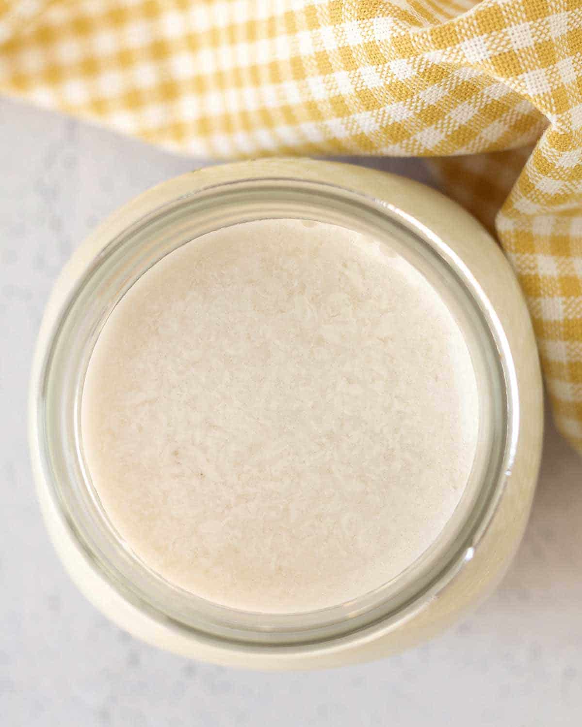 Image shows an overhead view of a mason jar of vegan buttermilk.