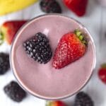 A close up shot of a dairy-free berry smoothie in a glass, smoothie is garnished with fresh berries.
