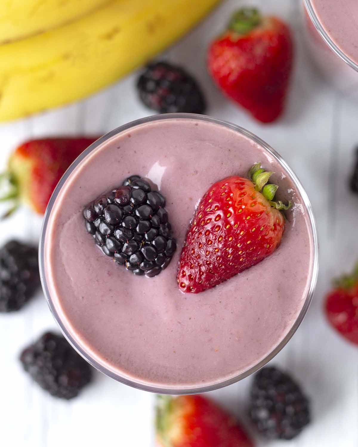 An overhead shot showing a banana berry smoothie in a glass.