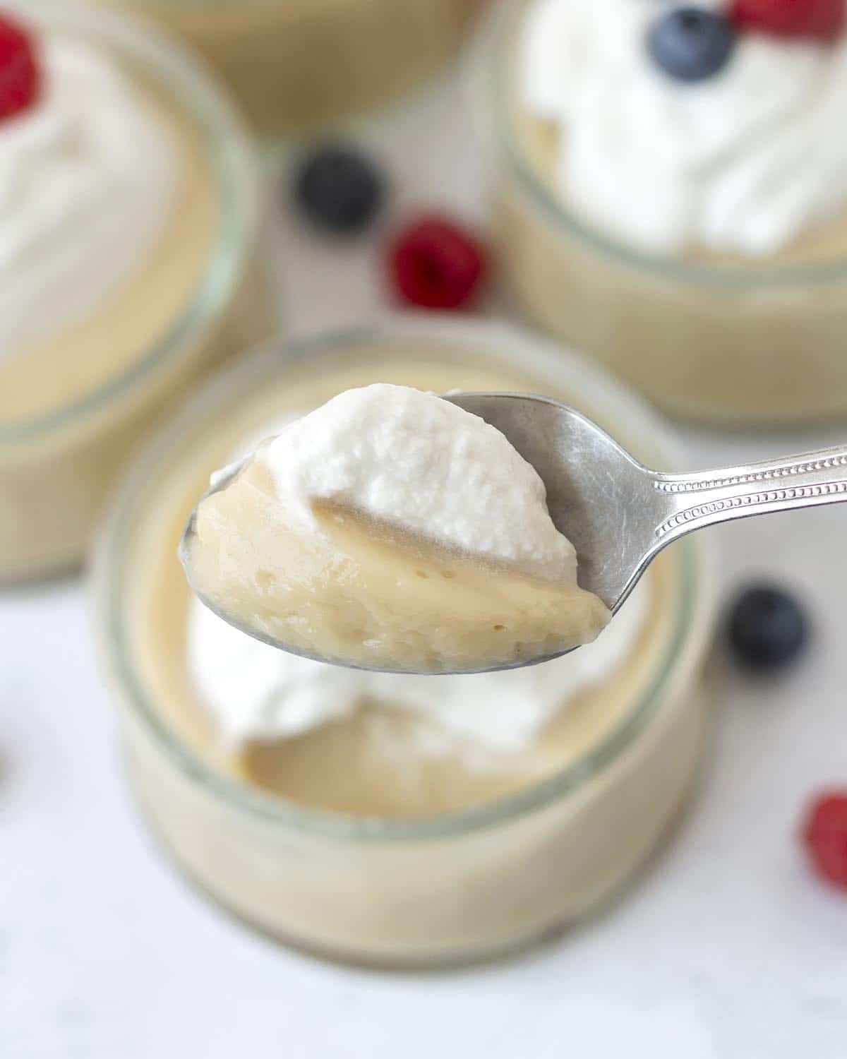 Eggless vanilla pudding and whipped cream on a spoon.