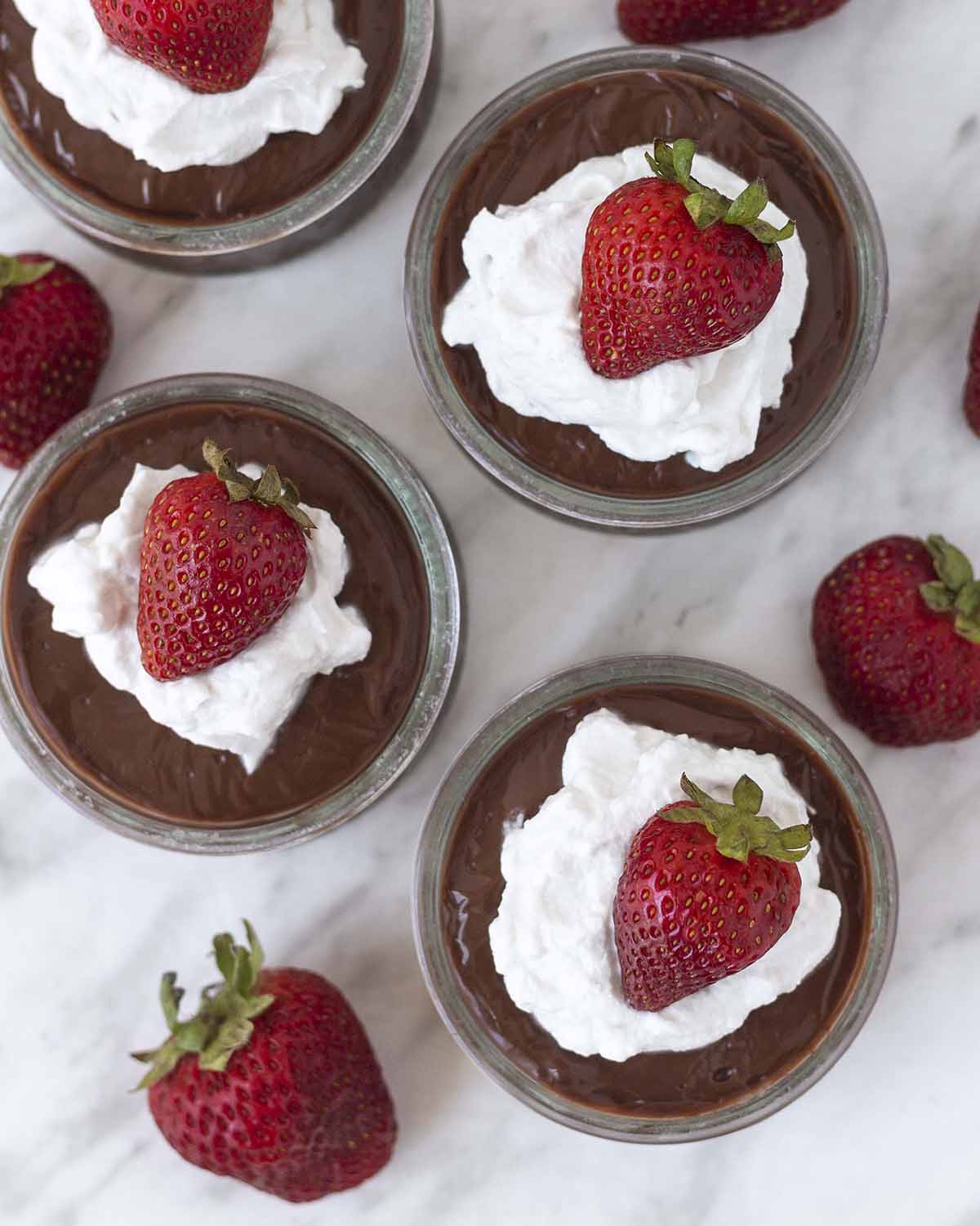 An overhead shot showing four bowls of dairy-free chocolate pudding on a table.