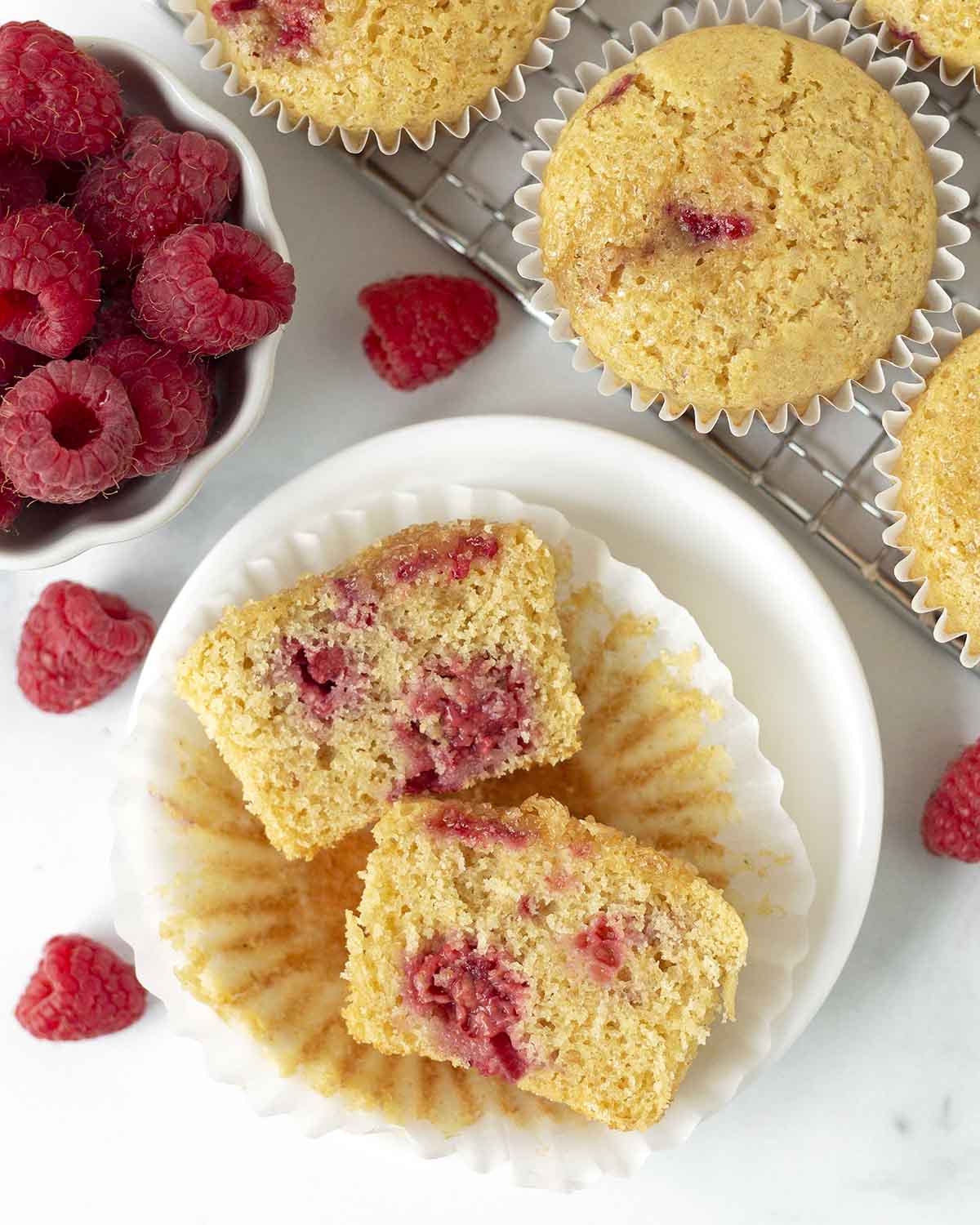 An overhead shot of a vegan raspberry muffin cut in half to show the fluffy inside.