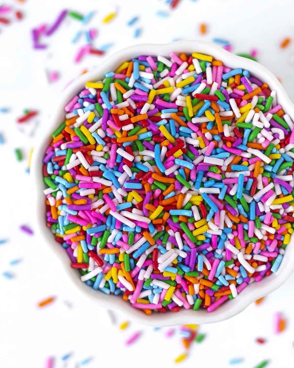An overhead shot of gluten-free vegan sprinkles in a small white ceramic bowl.