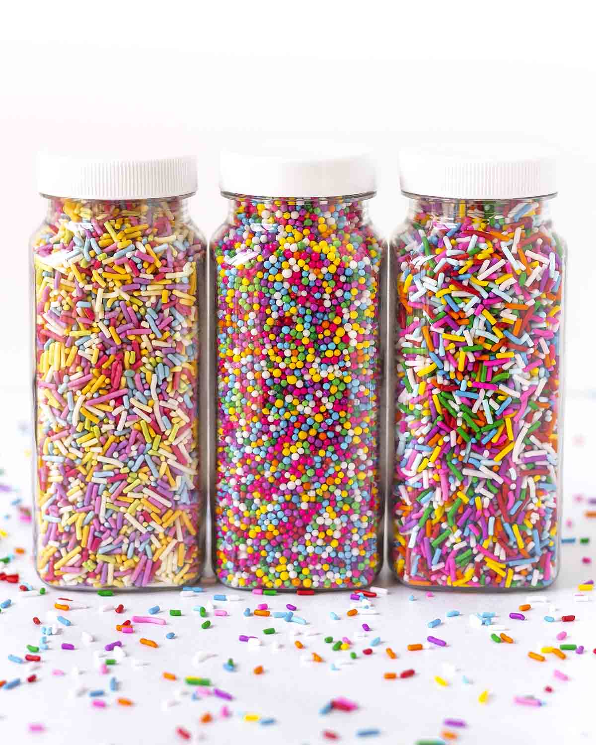 Three tall jars of vegan-friendly sprinkles lined up in a row.