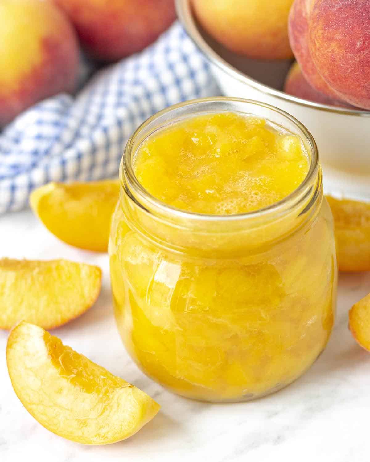 An overhead view showing an opened mason jar filled with homemade peach sauce.