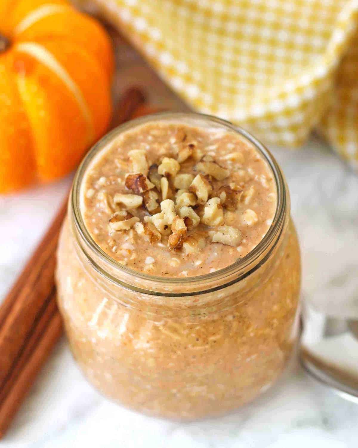 A jar of overnight pumpkin oats with chopped walnuts on top.