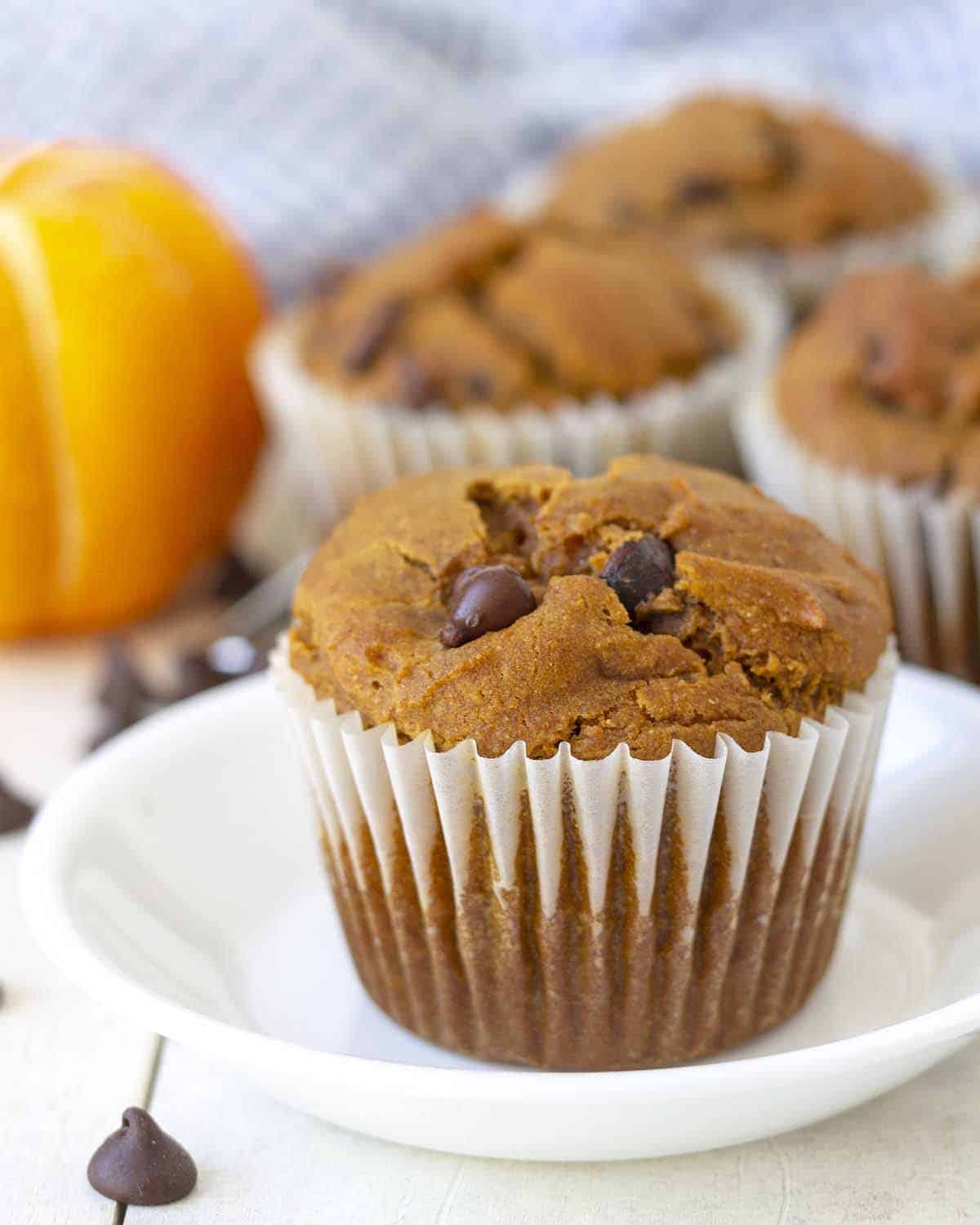 A vegan gluten-free pumpkin muffin on a small white plate.